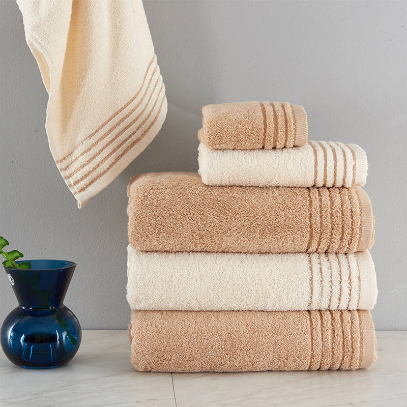 A neat, vertical stack of three towels (bath, hand, and washcloth sizes) with the top towel partially unfolded to drape over the side.