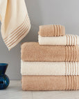 A neat, vertical stack of three towels (bath, hand, and washcloth sizes) with the top towel partially unfolded to drape over the side.